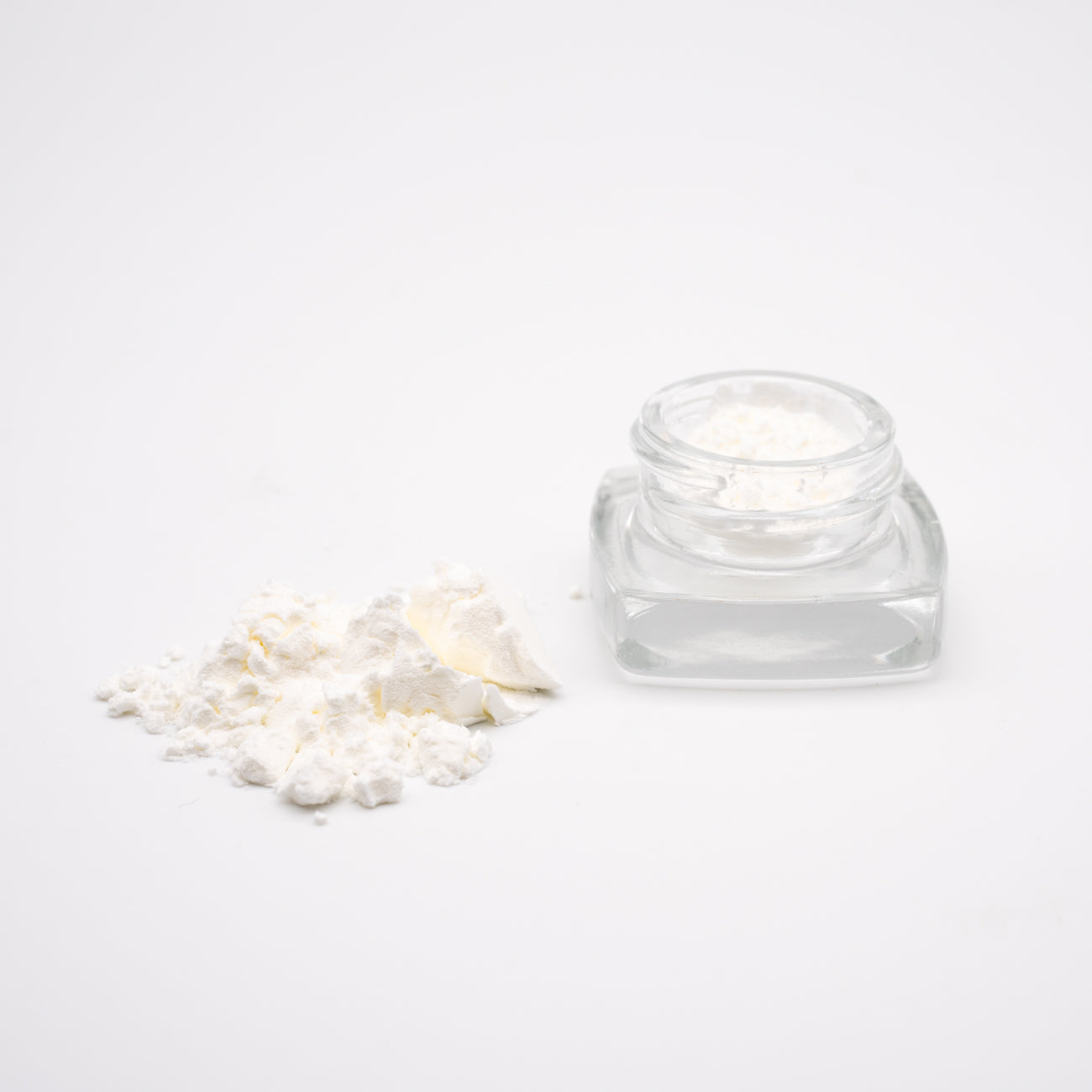 Clear glass cosmetic jar with loose white powder, featuring Oregon hemp CBD Isolate